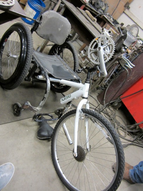 This picture shows the free hanging T-rod attached to the chair via the 2 2in tube sections that are welded to the chair. The T-rod is also feeding into the top tube of the bicycle frame creating the first of the three hand cycle attachment points.